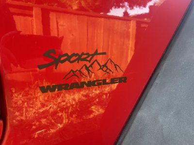 Custom vinyl decal on red Jeep Wrangler Sport with mountain design
