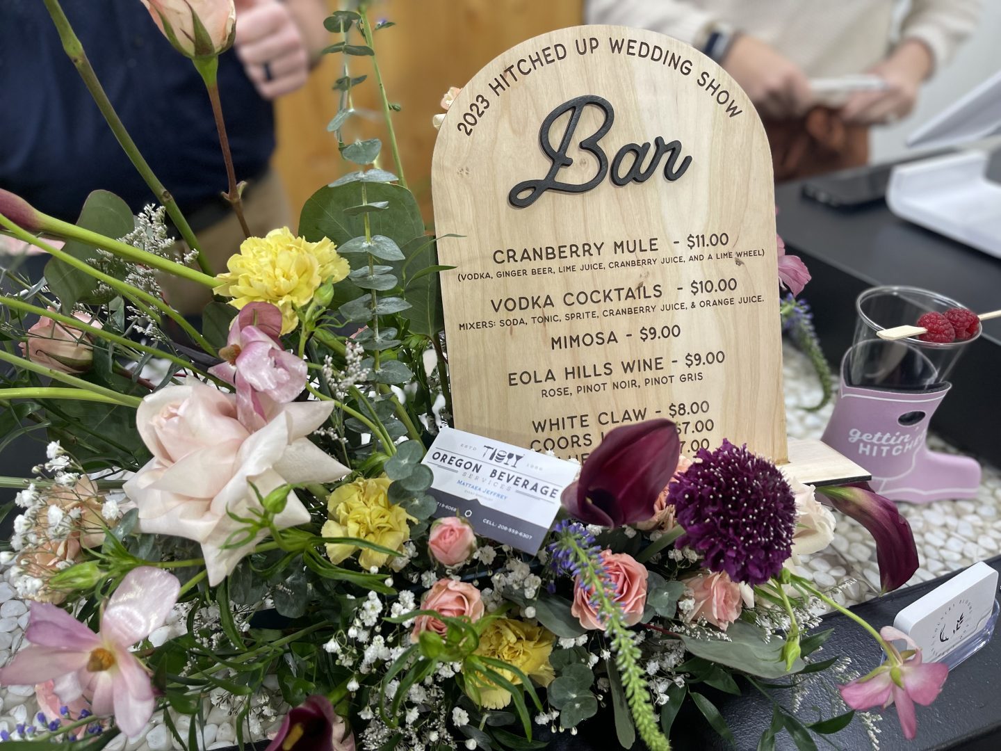 Laser engraved wooden wedding bar menu sign with cocktail prices and floral arrangement