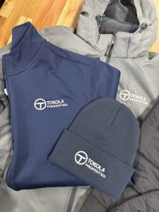Tokola Properties corporate branded apparel navy quarter zip gray rain jacket beanie real estate company